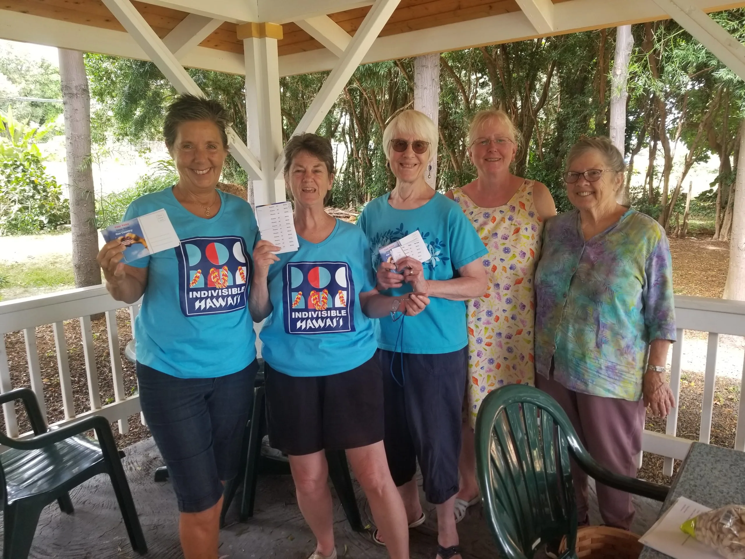 Group of people posing with their postcards at the weekly postcarding party in Kailua, hosted by the Blue Wave and Indivisible Windward Oahu.
