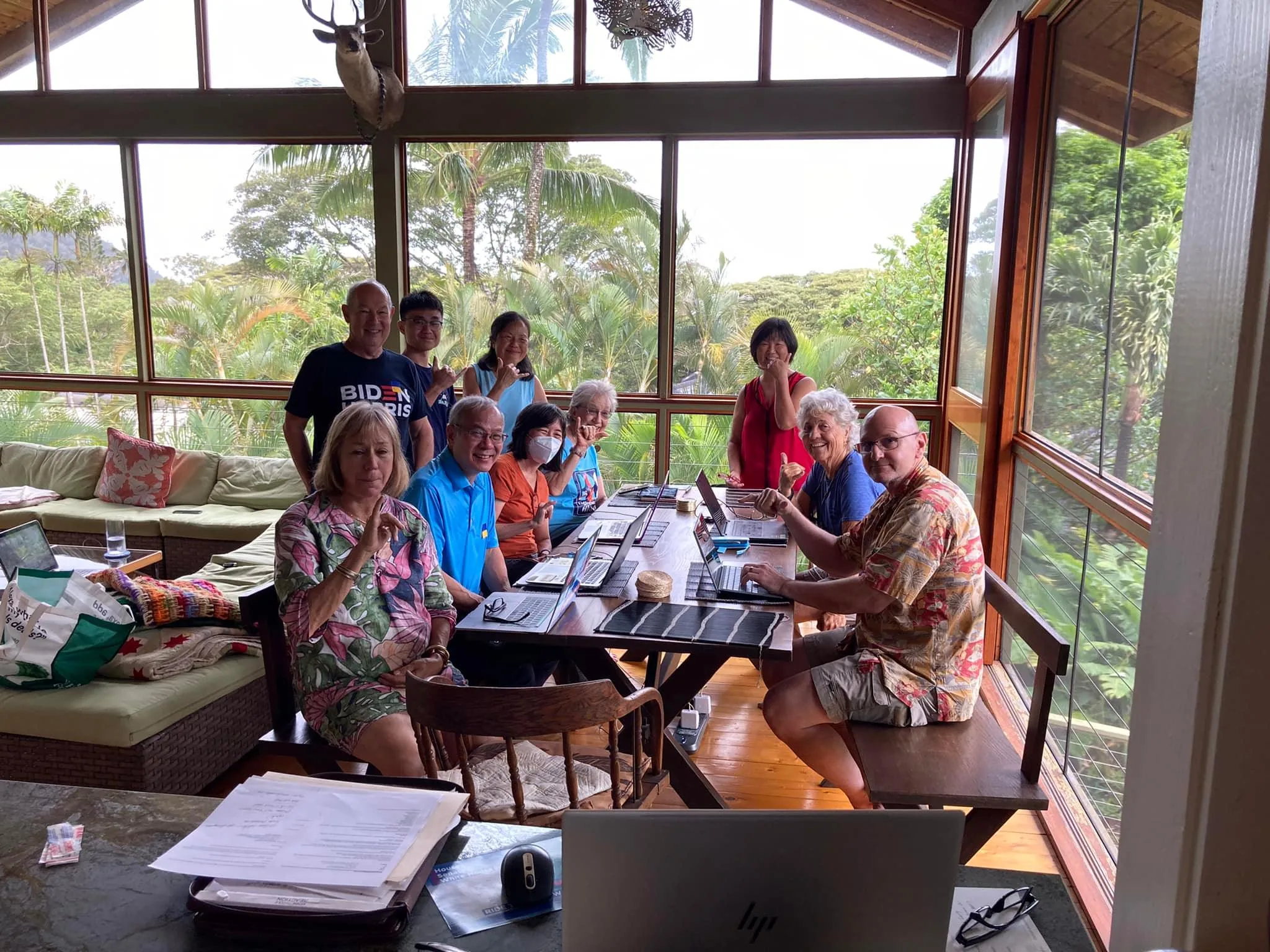 Group of people posing with their postcards at the weekly postcarding party in Kailua, hosted by the Blue Wave and Indivisible Windward Oahu.