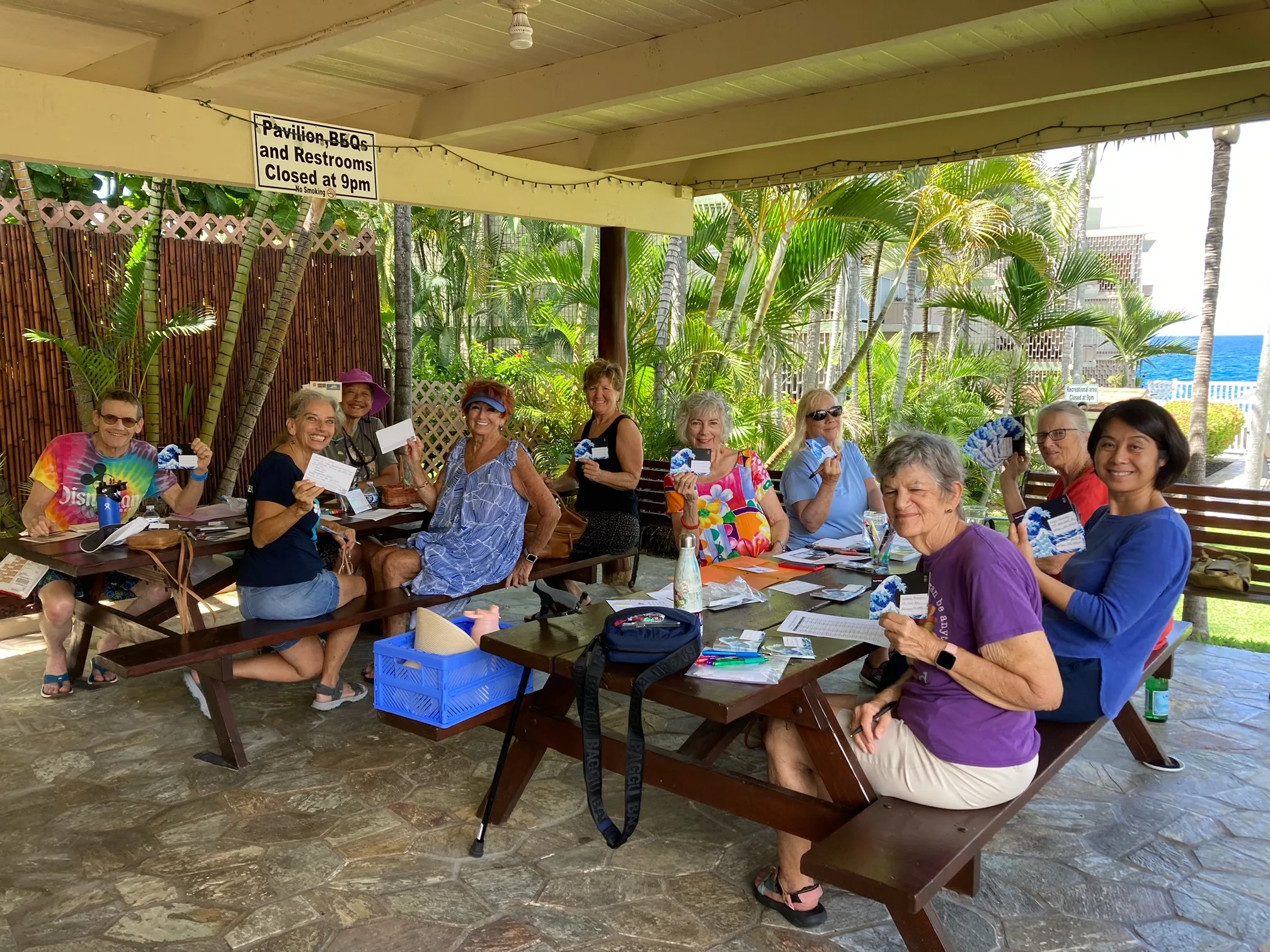 Group of people posing with their postcards at the weekly postcarding party in Kailua, hosted by the Blue Wave and Indivisible Windward Oahu.