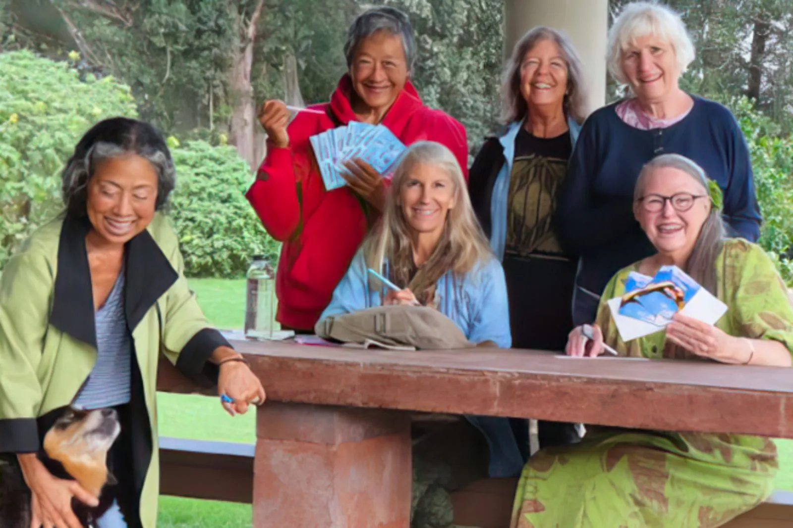 Indivisible Waimea postcarding team posing with postcards - and a dog